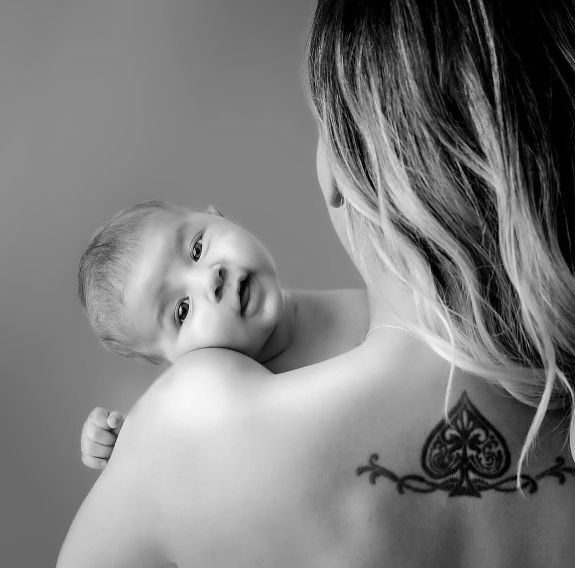 Mother holding her newborn baby in soft window light